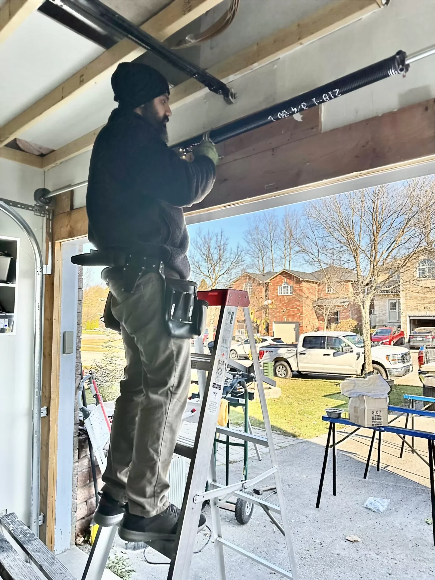Garage door technician repairing a torsion spring on a residential garage door
